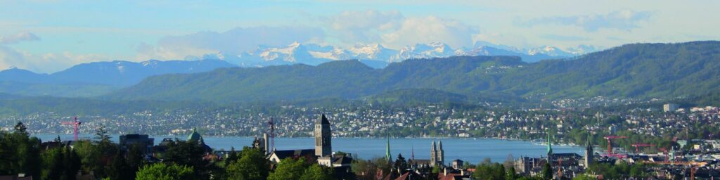 Blick von der reformierten Kirche Oberstrass über die Stadt Zürich und das Seebecken auf die Alpen